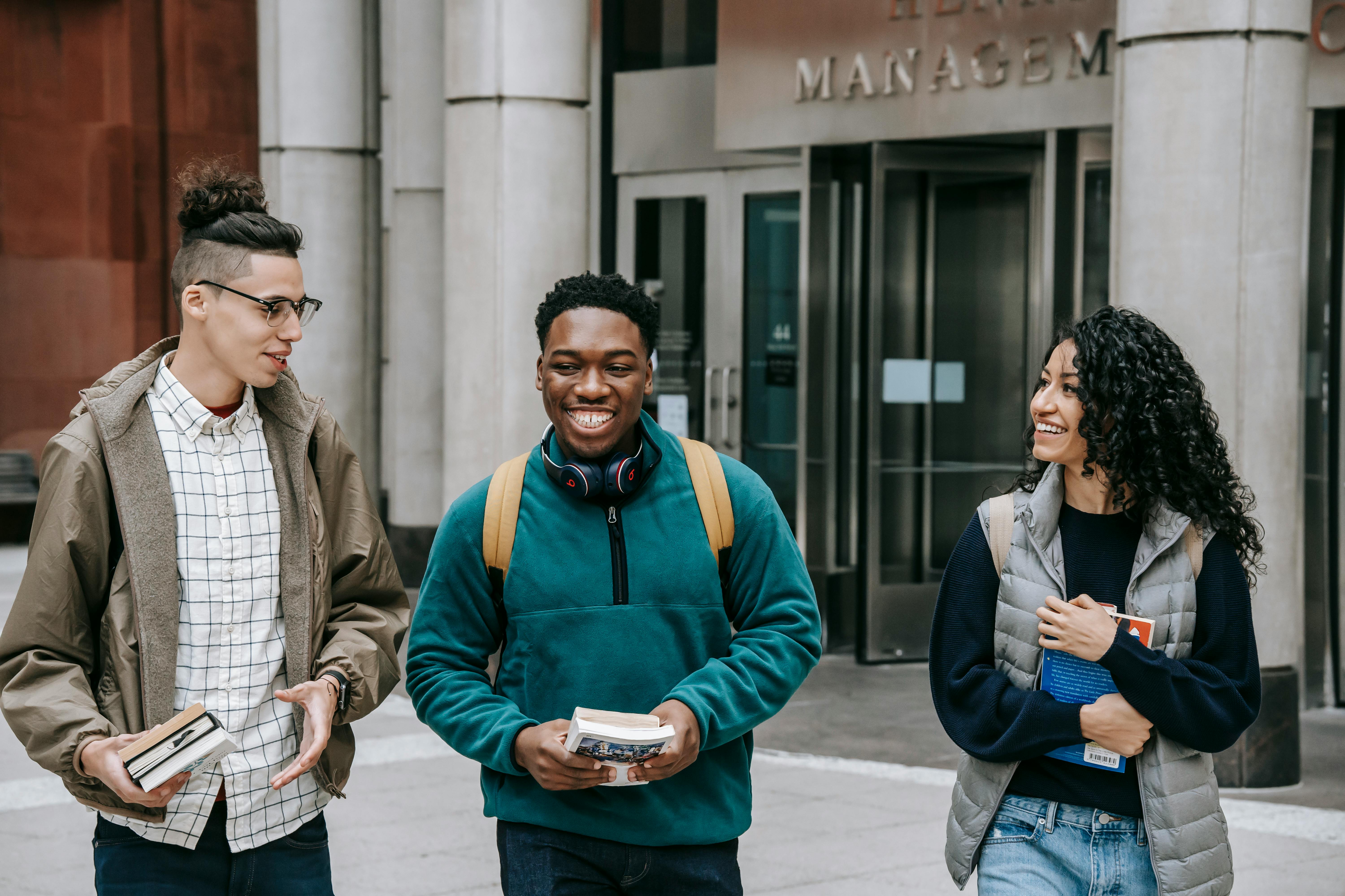 Happy diverse students walking outside modern university building in Sydney